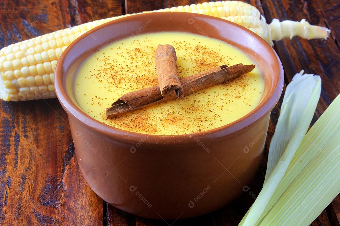 Curau, creme de milho doce e sobremesa típica da culinária brasileira, com canela colocada em tigela de cerâmica na mesa de madeira