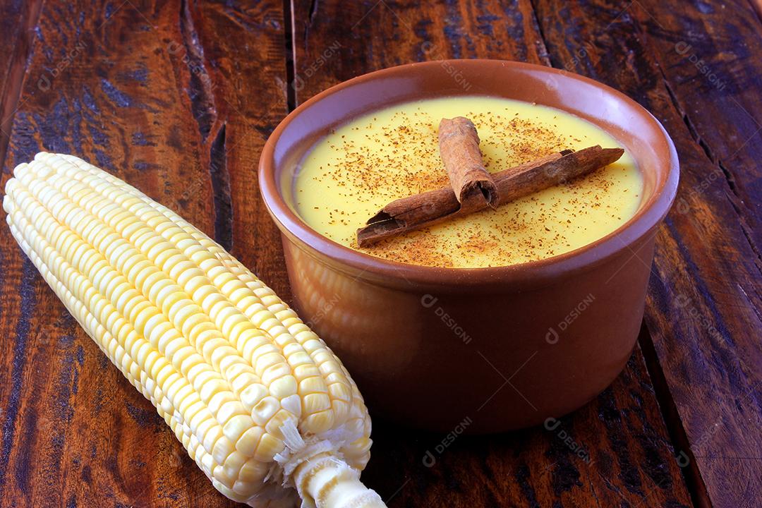 Curau, creme de milho doce e sobremesa típica da culinária brasileira, com canela colocada em tigela de cerâmica na mesa de madeira