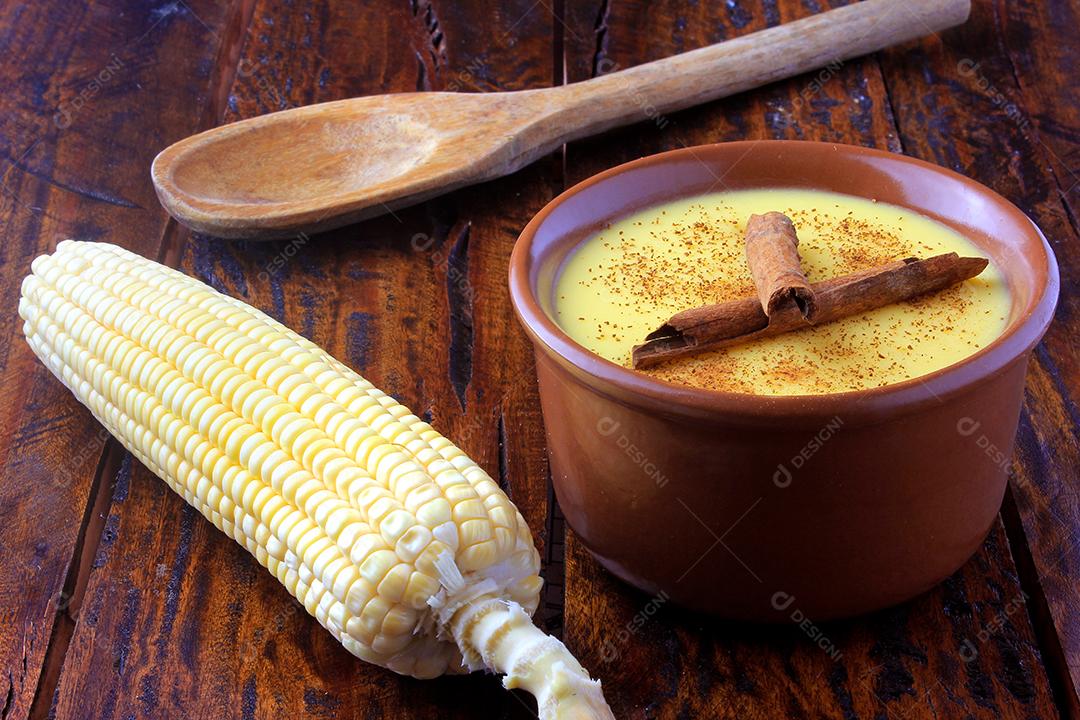 Curau, creme de milho doce e sobremesa típica da culinária brasileira, com canela colocada em tigela de cerâmica na mesa de madeira