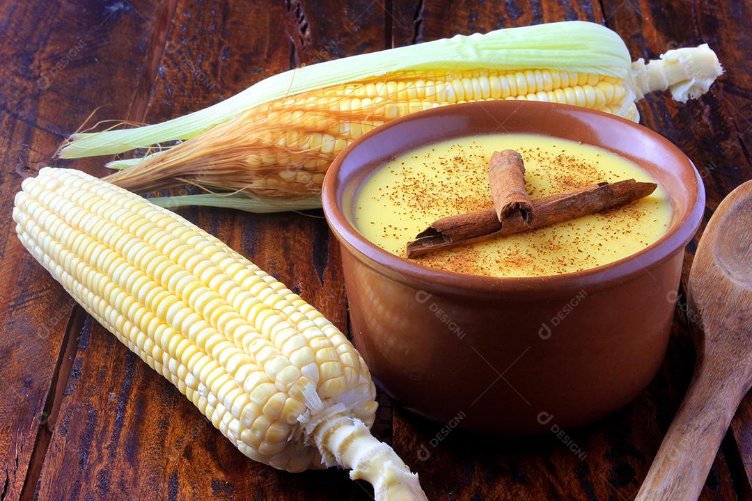 Curau, creme de milho doce e sobremesa típica da culinária brasileira, com canela colocada em tigela de cerâmica na mesa de madeira