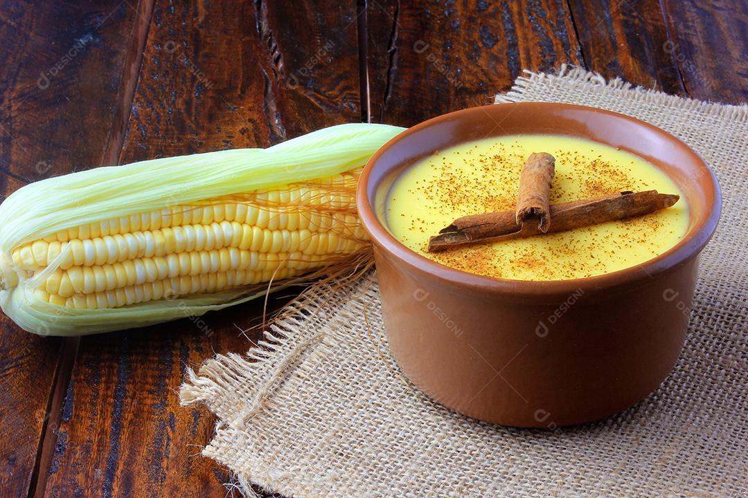 Curau, creme de milho doce e sobremesa típica da culinária brasileira, com canela colocada em tigela de cerâmica na mesa de madeira