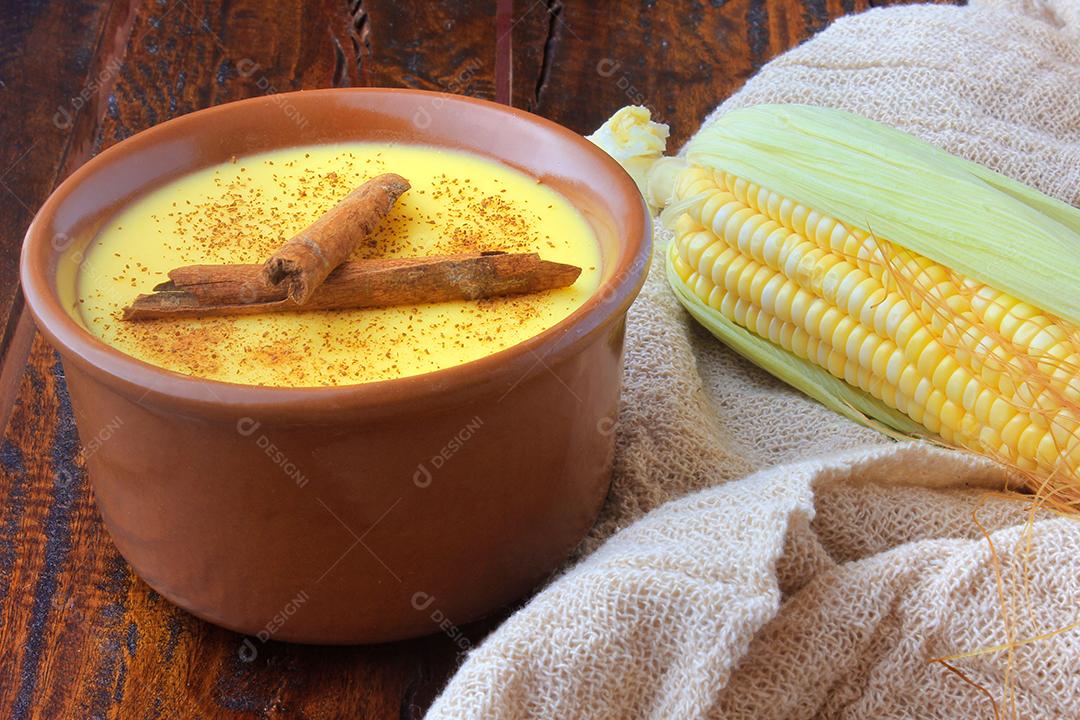 Curau, sweet corn cream and typical dessert of Brazilian cuisine, with cinnamon placed in ceramic bowl on wooden table
