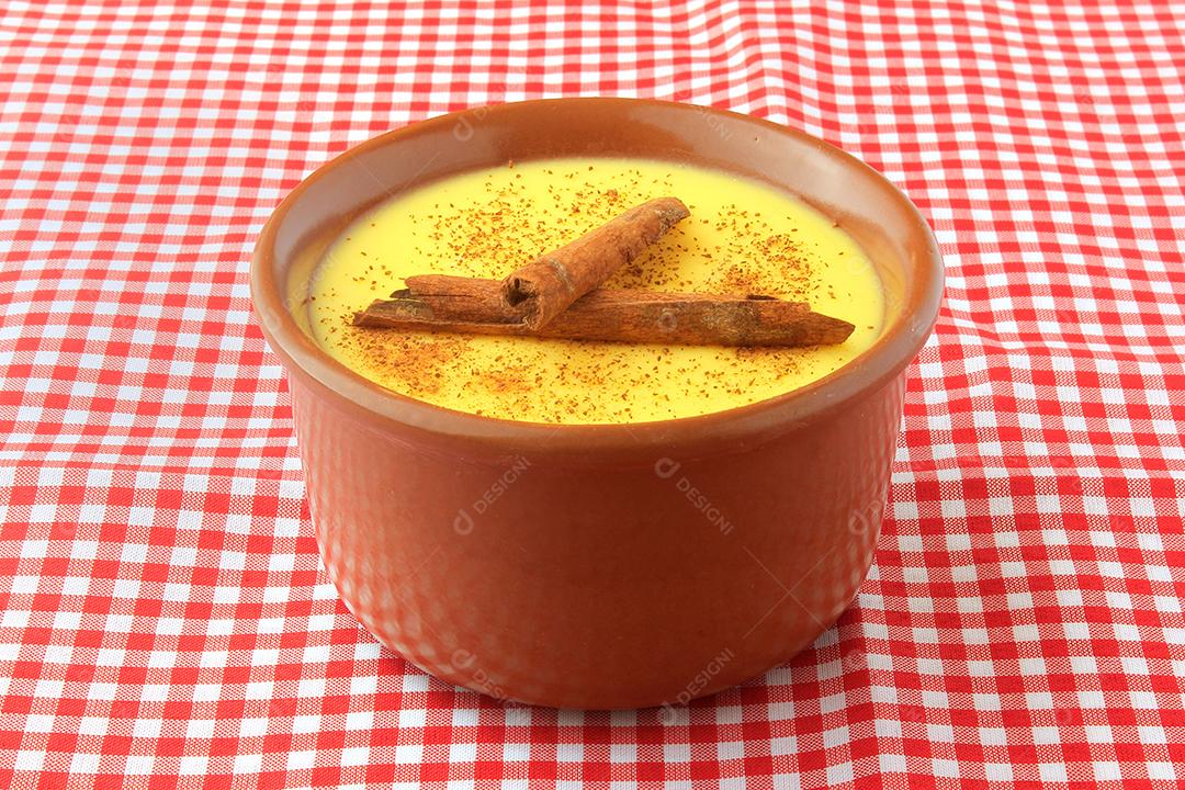 curau, creme de milho doce e sobremesa típica da culinária brasileira, com canela colocada em tigela de cerâmica sobre toalha xadrez