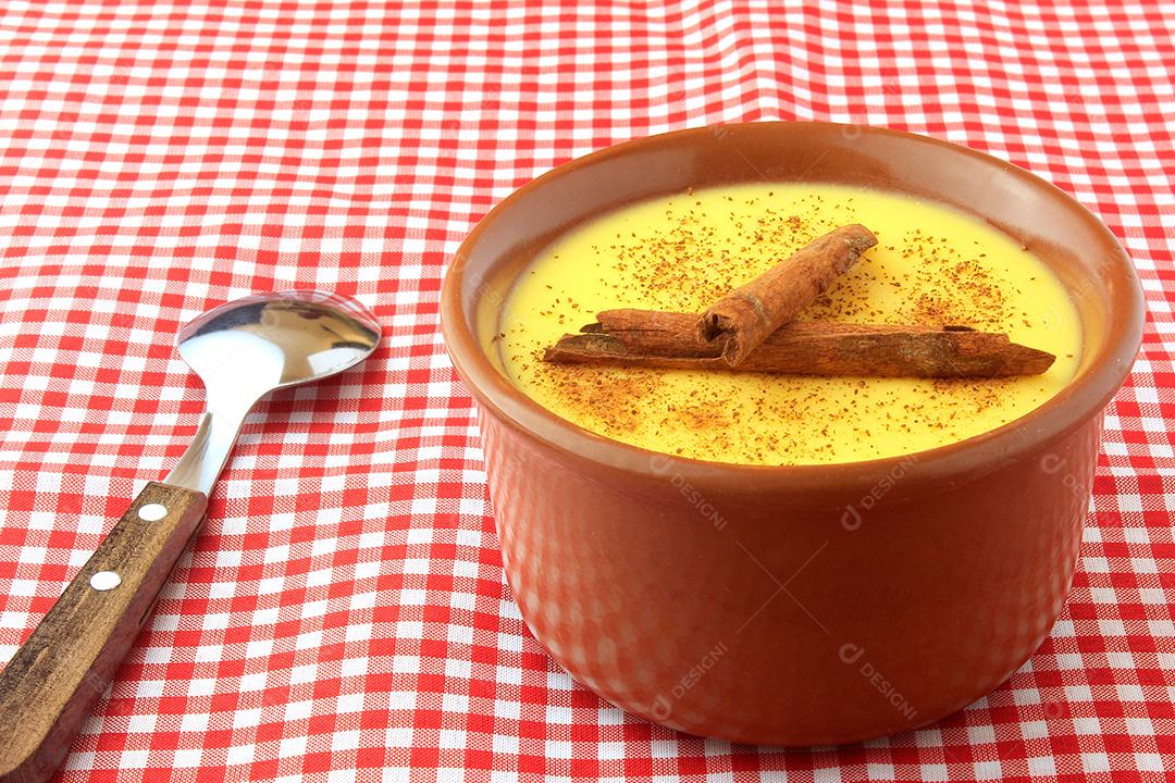 curau, creme de milho doce e sobremesa típica da culinária brasileira, com canela colocada em tigela de cerâmica sobre toalha xadrez