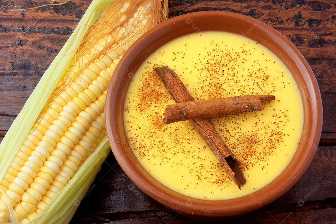 Curau, creme de milho doce e sobremesa típica da culinária brasileira, com canela colocada em tigela de cerâmica na mesa de madeira