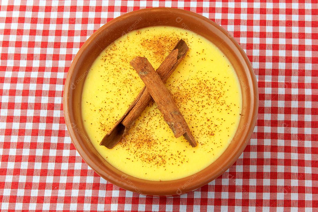 Curau creme de milho doce com canela colocada em tigela de cerâmica em pano xadrez