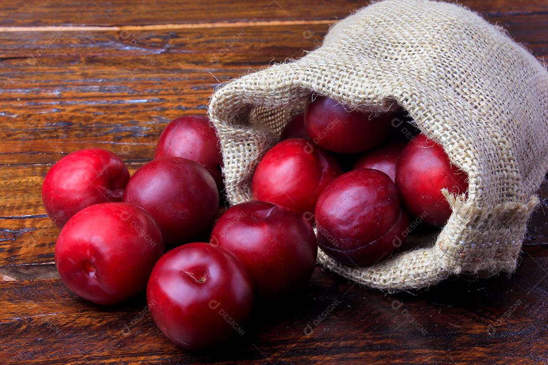 Ameixas orgânicas cruas e frescas na mesa de madeira rústica