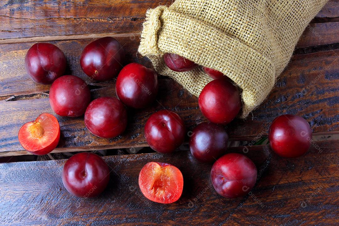 Ameixas orgânicas cruas e frescas na mesa de madeira rústica