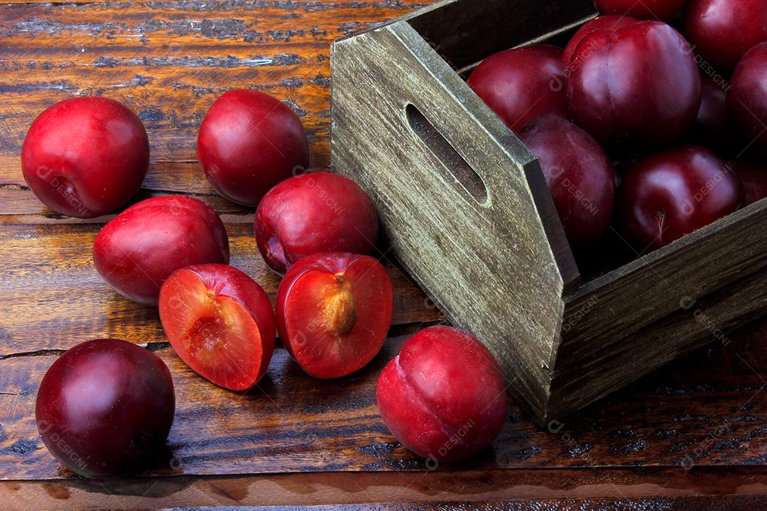 Ameixas orgânicas cruas e frescas na mesa de madeira rústica