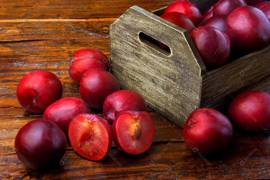 Ameixas orgânicas cruas e frescas na mesa de madeira rústica