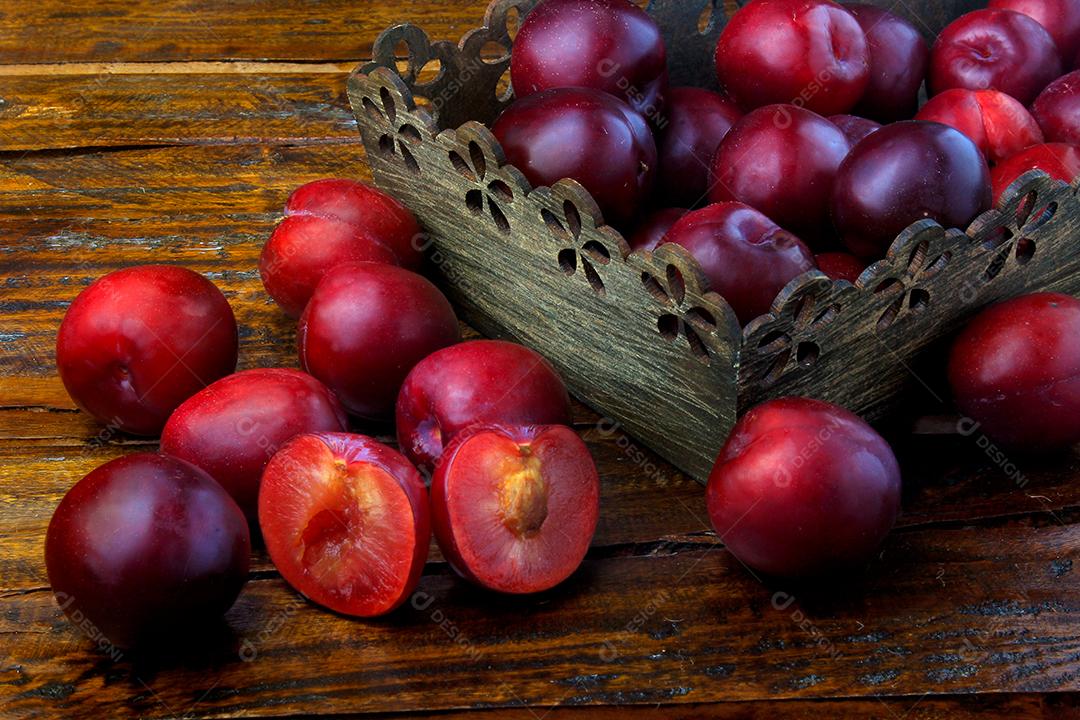 Ameixas orgânicas cruas e frescas na mesa de madeira rústica