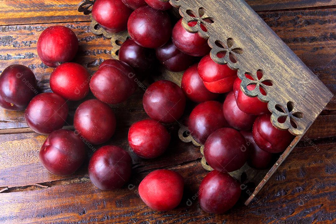 Ameixas orgânicas cruas e frescas na mesa de madeira rústica