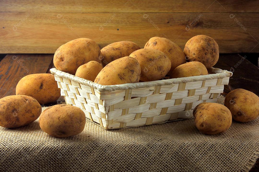 Batatas frescas e cruas colhidas da plantação e colocadas em caixa rústica na mesa de madeira