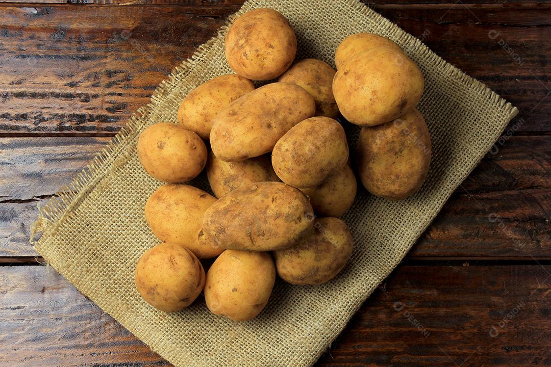 pilha de batatas frescas e cruas colhidas da plantação e colocadas em caixa rústica na mesa de madeira