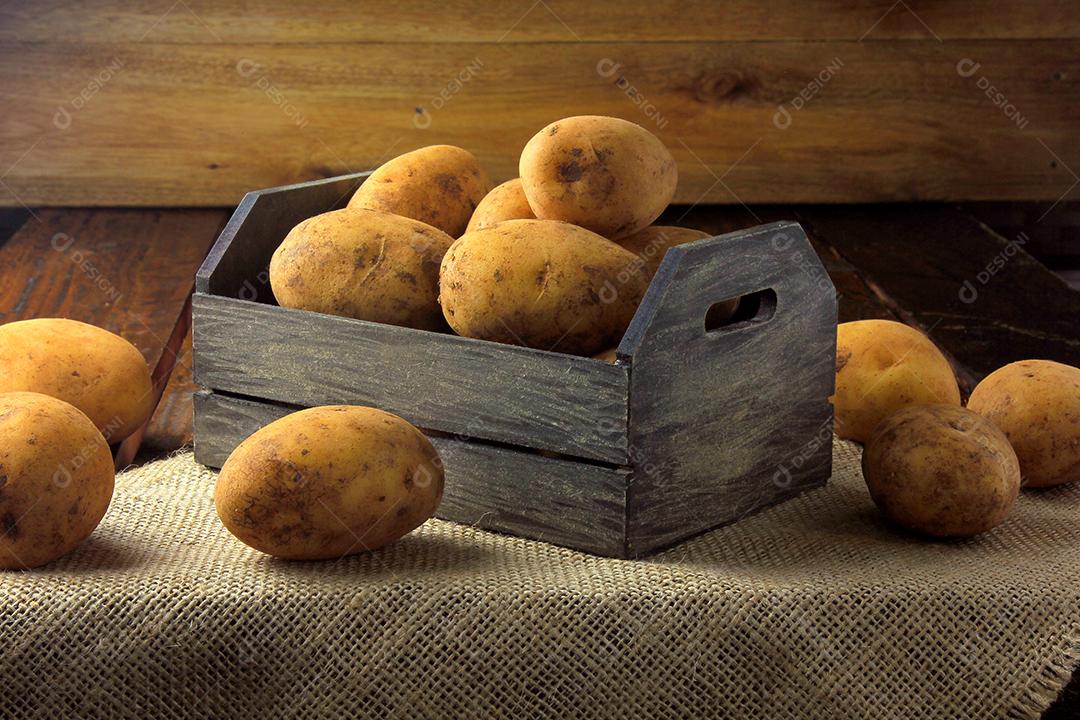 pilha de batatas frescas e cruas colhidas da plantação e colocadas em caixa rústica na mesa de madeira