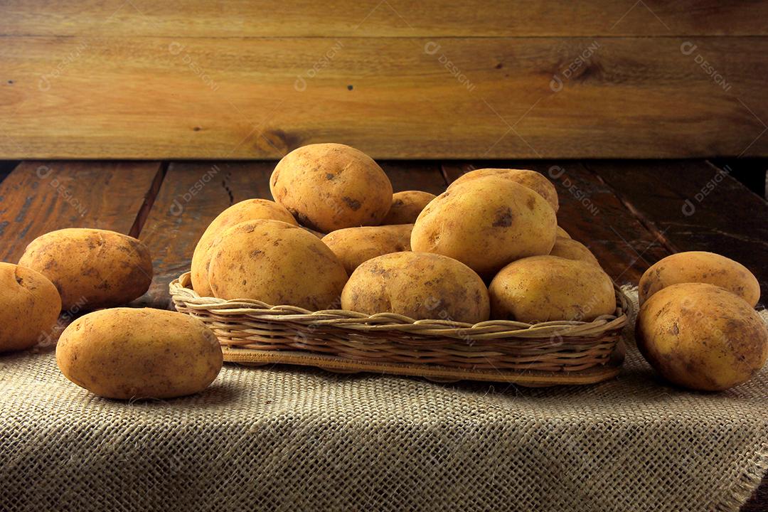 pilha de batatas frescas e cruas colhidas da plantação e colocadas em caixa rústica na mesa de madeira