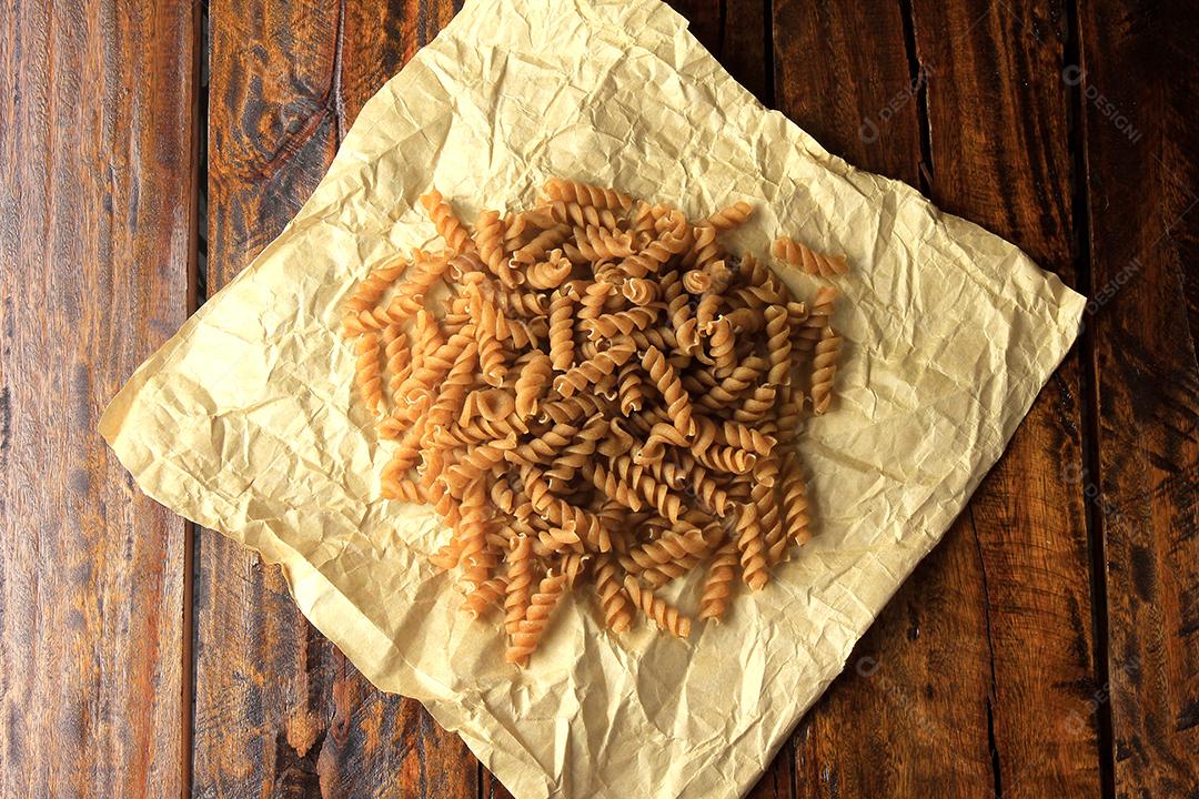 Vista superior Massa integral fusilli grãos inteiros orgânicos crus em uma madeira rústica