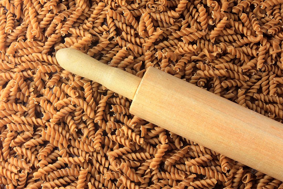 Vista superior de toda a massa Fusilli com colher de pau sobre um fundo de madeira