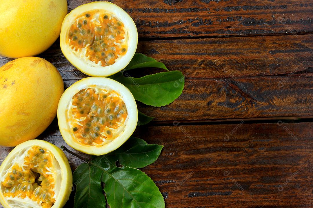 maracujá amarelo com folhas e cortado ao meio na mesa de madeira rústica. Espaço livre para texto. Vista do topo