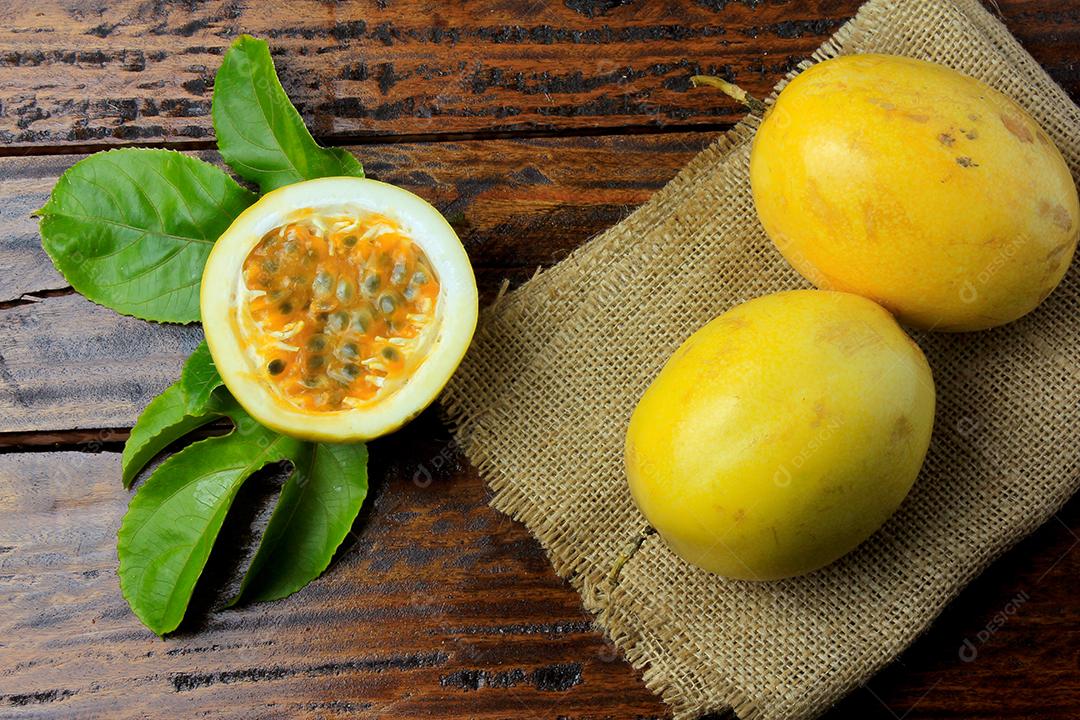 maracujá amarelo com folhas e cortado ao meio em tecidos de saco rústico na mesa de madeira. Vista do topo