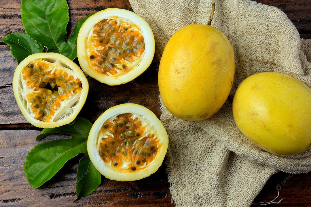 maracujá amarelo com folhas e cortado ao meio em tecidos de saco rústico na mesa de madeira. Vista do topo