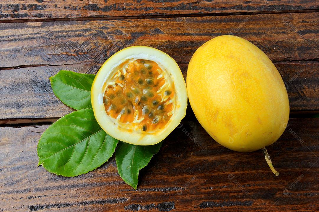 maracujá amarelo com folhas e maracujá cortado ao meio isolado na mesa de madeira. Vista do topo