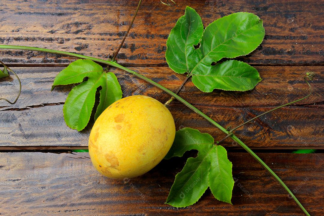 ramos e folhas com maracujá amarelo isolados na mesa de madeira. Vista superior de perto