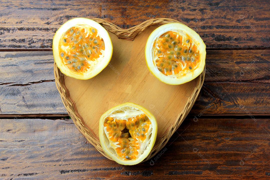 polpa de maracujá na colher de pau ao lado de maracujá inteiro com folha na mesa de madeira