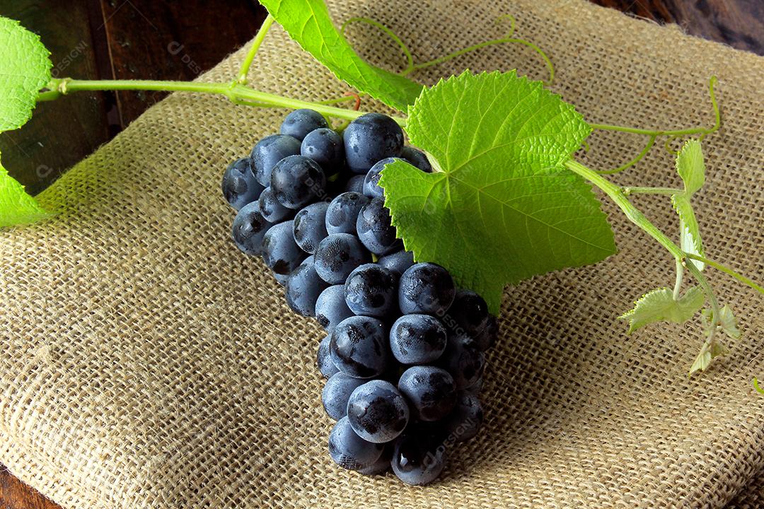 cachos de uvas frescas com galhos e folhas na mesa de madeira rústica