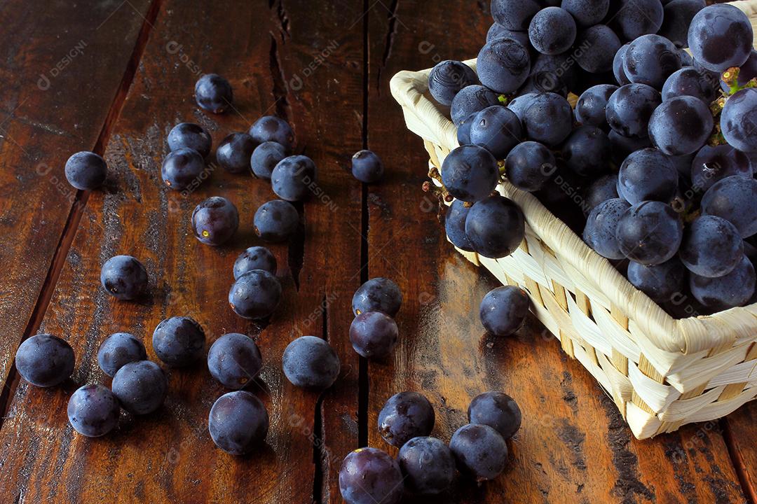 cachos de uvas, dentro da cesta de fibra de bambu na mesa de madeira, vista de perto
