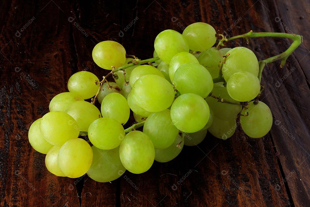 cachos de uvas verdes frescas, na mesa de madeira rústica