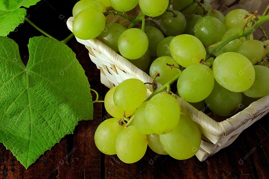 cachos de uvas verdes frescas, na mesa de madeira rústica