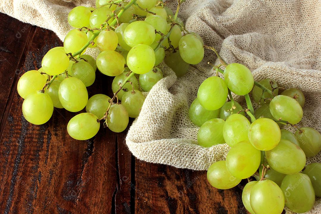 cachos de uvas, dentro da cesta de fibra de bambu na mesa de madeira, vista de perto
