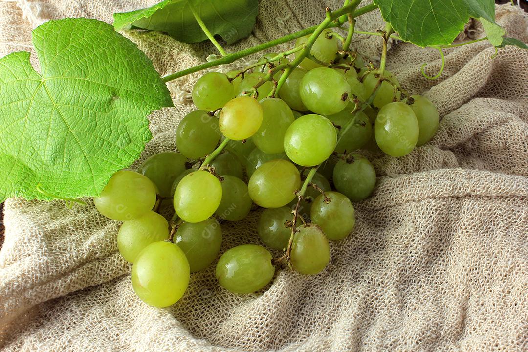 cachos de uvas, dentro da cesta de fibra de bambu na mesa de madeira