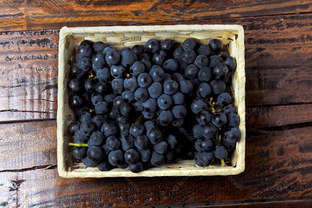 cachos de uva dentro da cesta com forma de coração na mesa de madeira