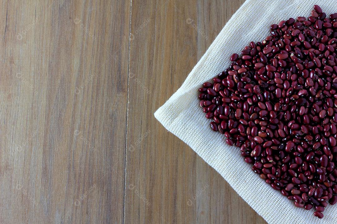 grãos de feijão vermelho no saco no lado da mesa de madeira, vista superior