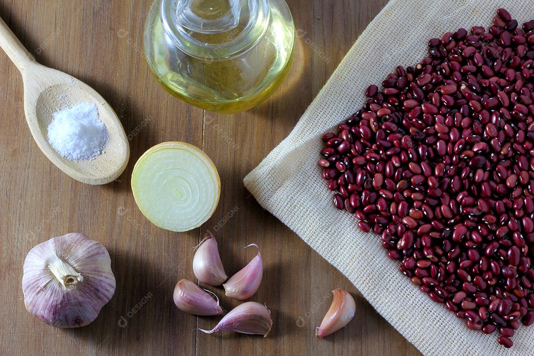 grãos de feijão vermelho e ingredientes na mesa de madeira, vista superior