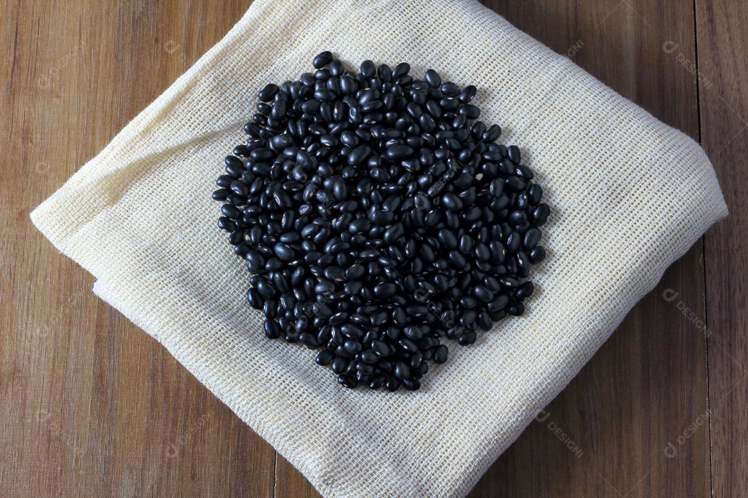 grãos de feijão preto no saco no lado da mesa de madeira, vista superior