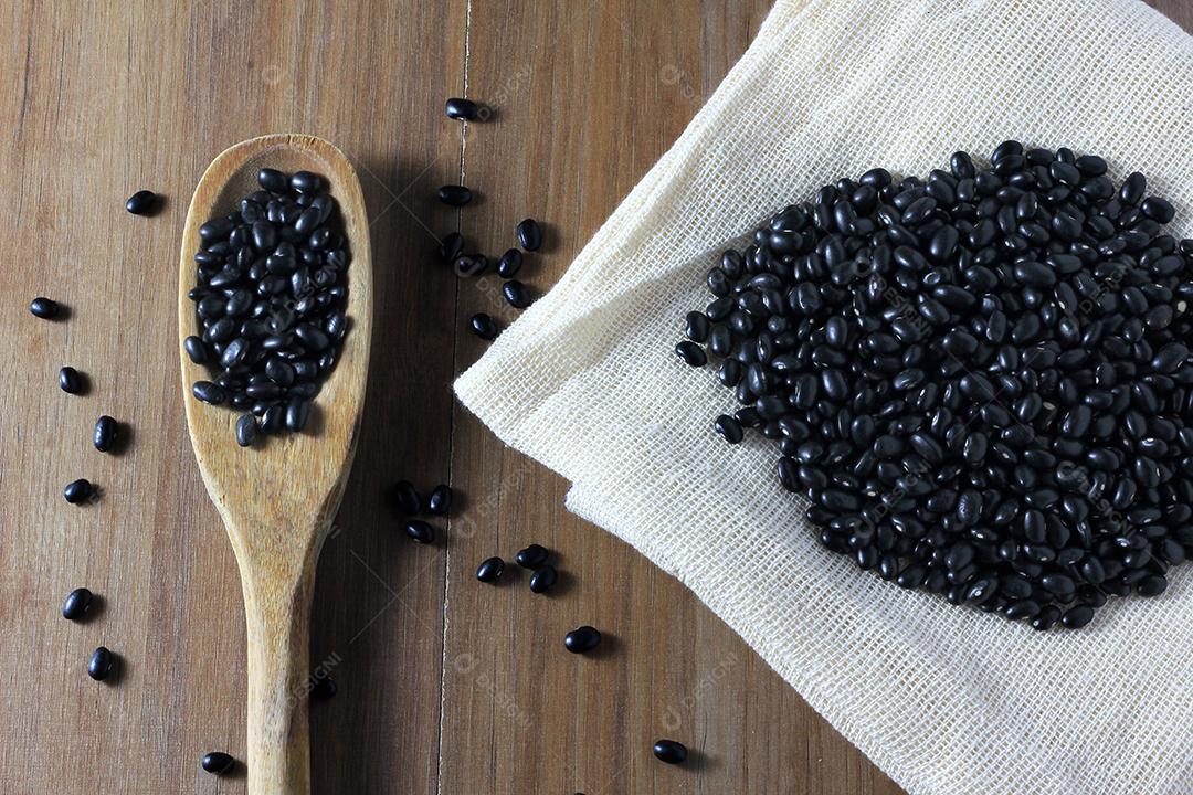 grãos de feijão preto no saco no lado da mesa de madeira, vista superior