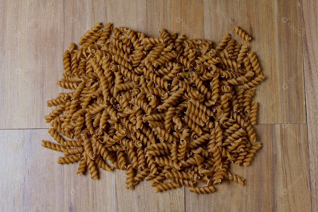 porção de macarrão inteiro cru, torcido, mesa de madeira, vista superior