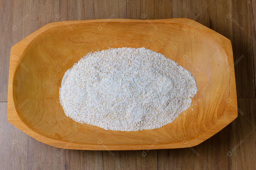 porção de farinha de trigo integral crua, tigela de madeira, mesa de madeira, vista superior