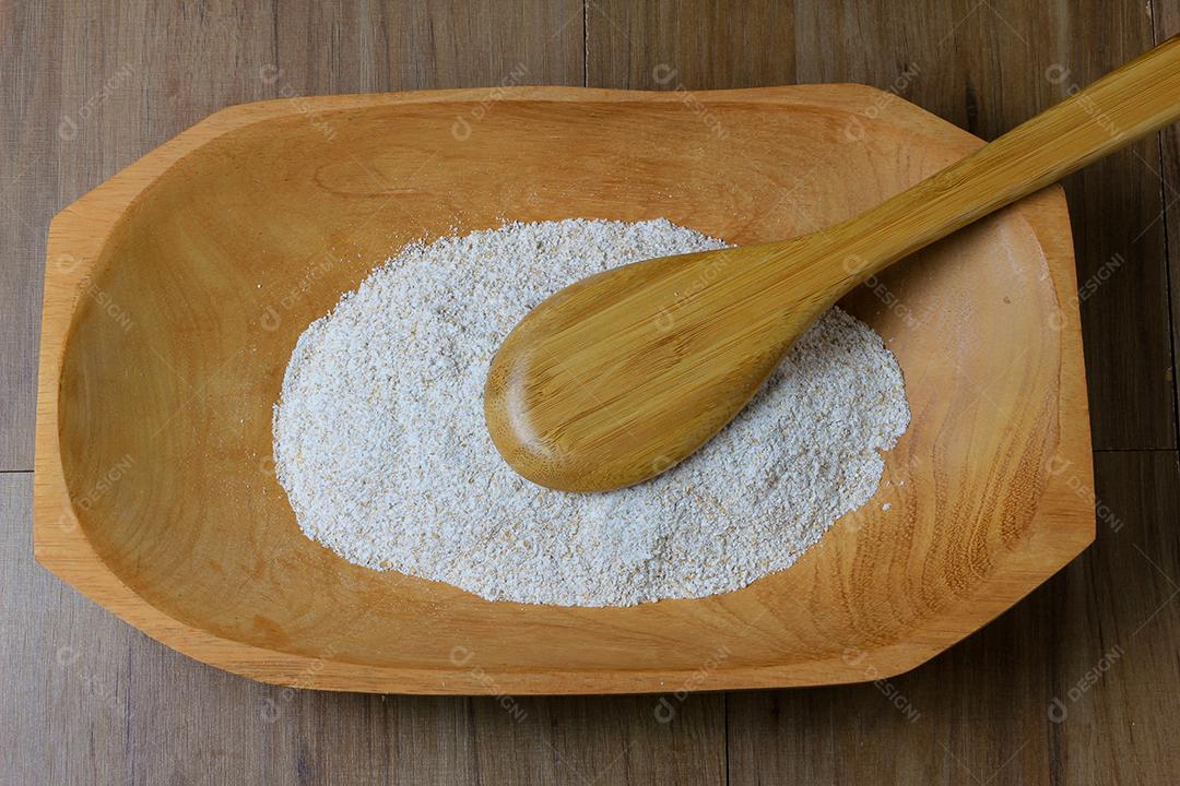 porção de farinha de trigo integral crua, tigela de madeira, mesa de madeira, vista superior