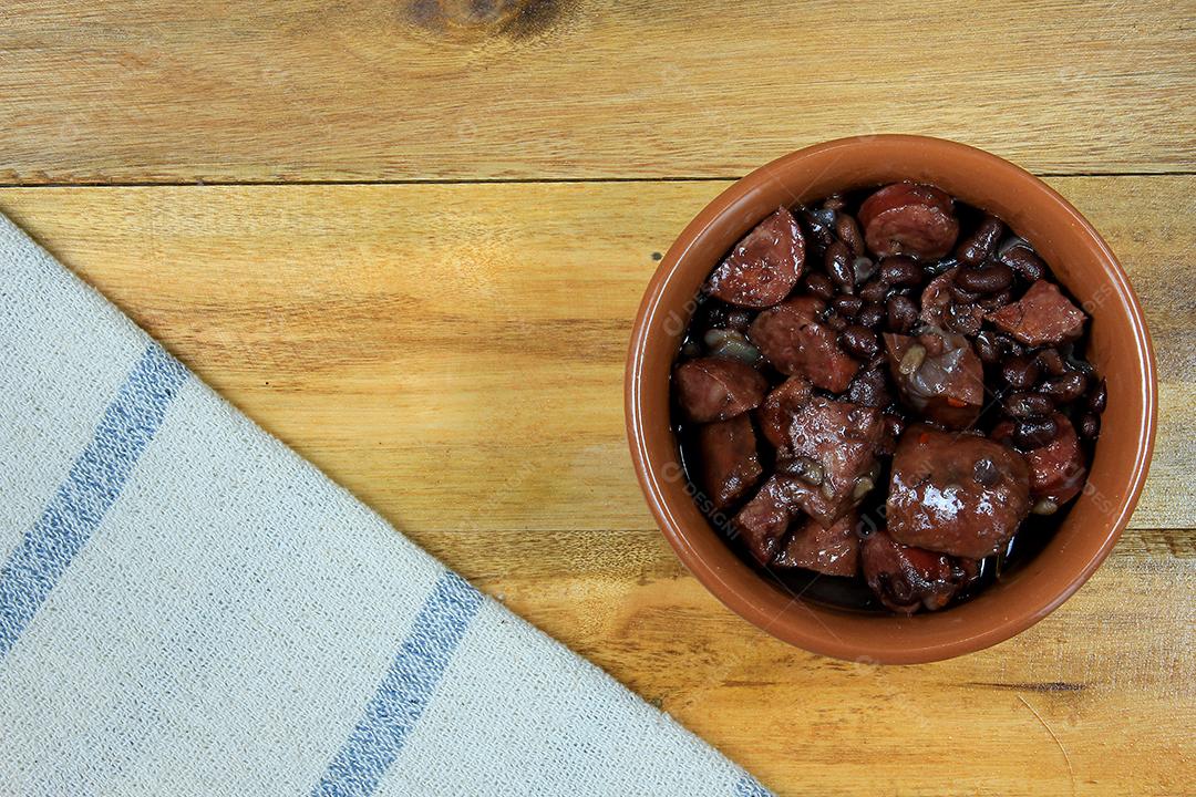 pote com feijoada, prato da cozinha tradicional brasileira, isolado sob fundo de madeira, vista superior