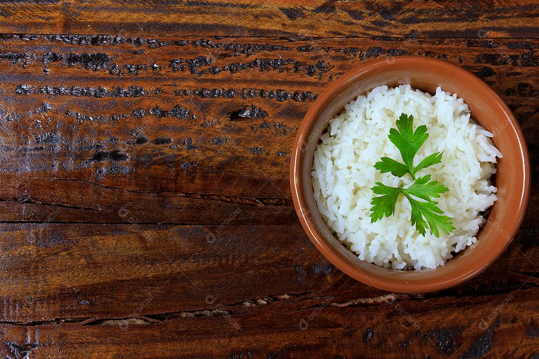 arroz branco dentro de panela de cerâmica na mesa de madeira, vista superior