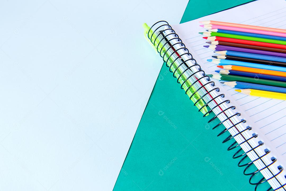 Material escolar, caderno, caneta e lápis de cor.