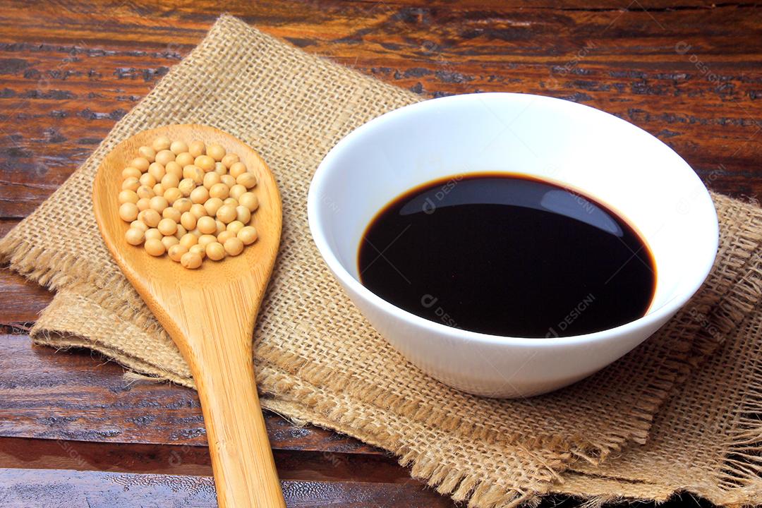 molho de soja escuro em uma tigela de cerâmica branca isolada na mesa de madeira rústica