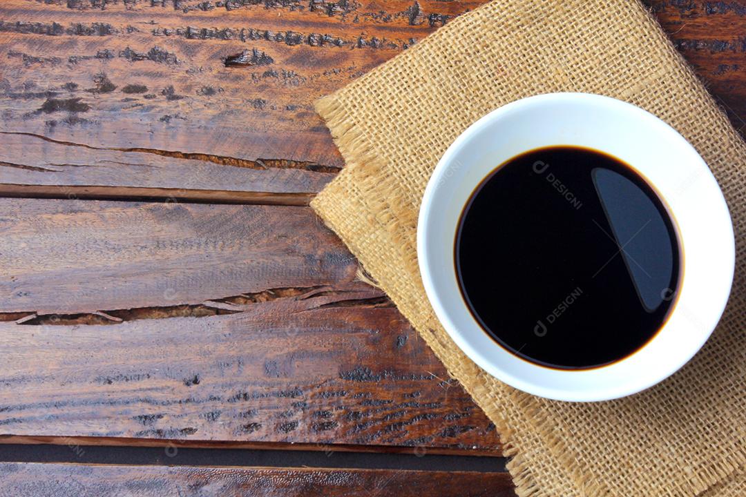 molho de soja escuro em uma tigela de cerâmica branca isolada na mesa de madeira rústica
