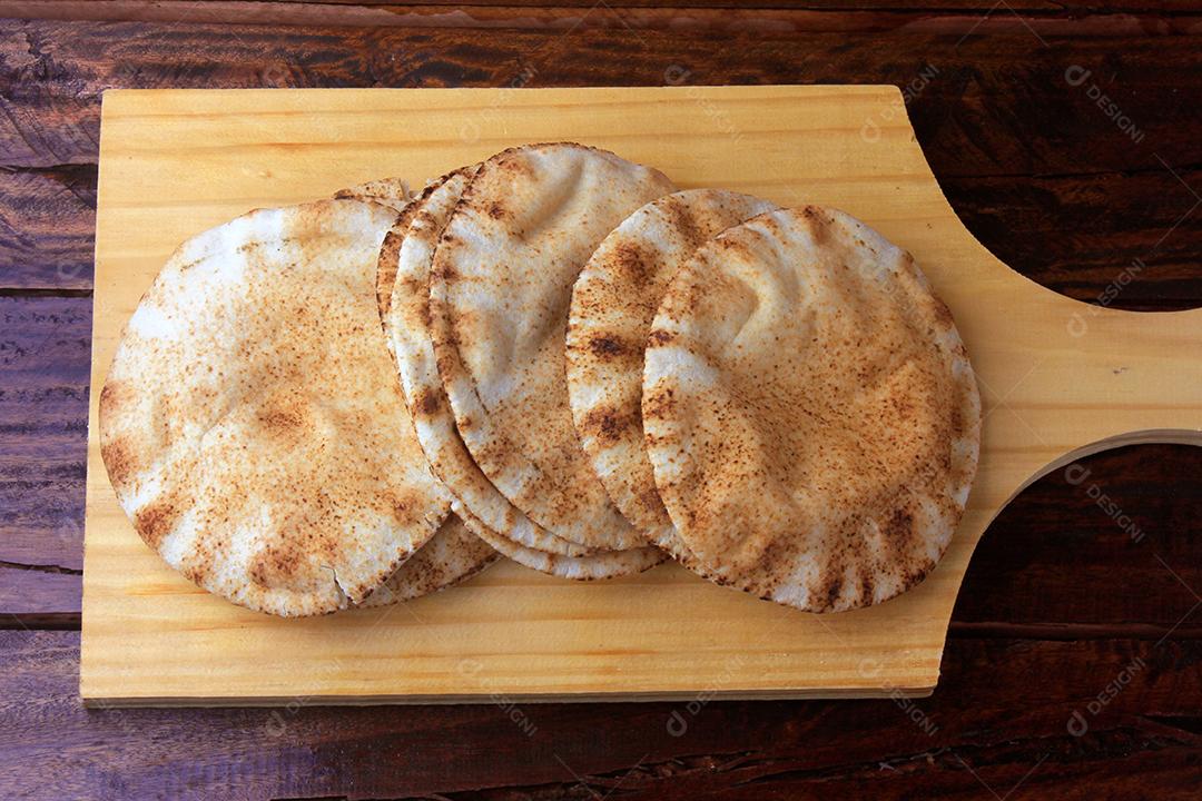 Pão pita isolado na espátula de madeira saindo do forno. Comida tradicional e típica da culinária árabe