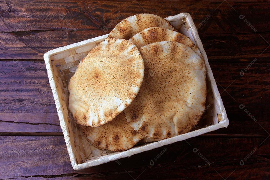 Pão pita isolado em fundo branco na cesta de café da manhã, na mesa de madeira rústica Comida tradicional e típica da cozinha árabe