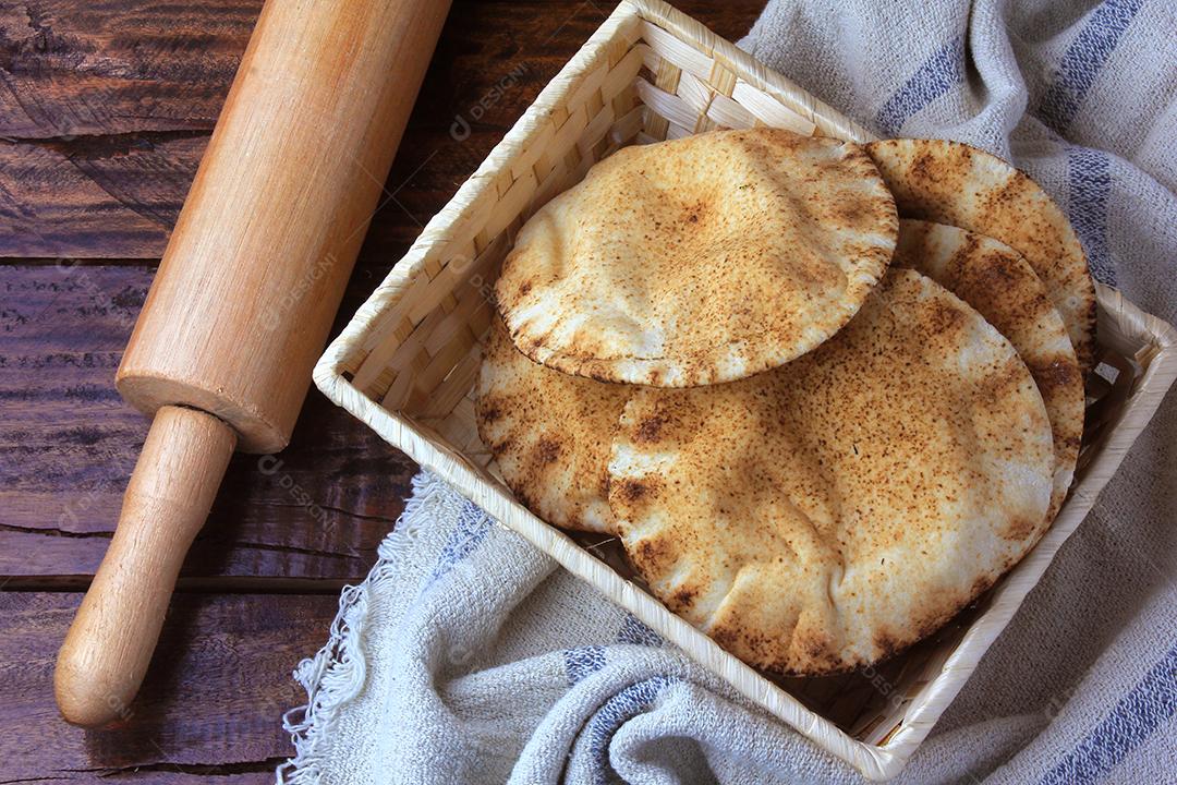Pão pita isolado em fundo branco na cesta de café da manhã, na mesa de madeira rústica Comida tradicional e típica da cozinha árabe